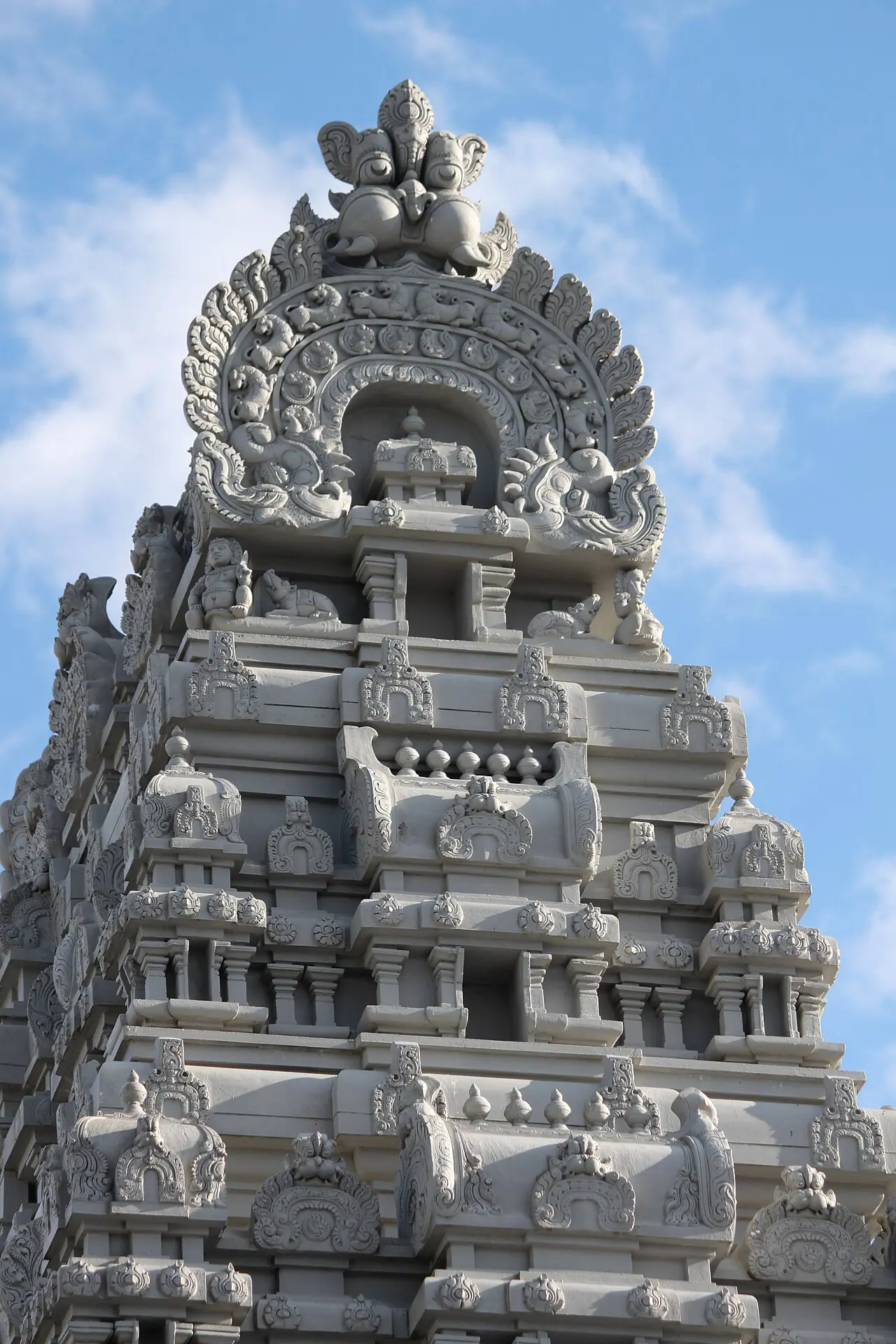 నీలి ఆకాశం నేపథ్యంలో, క్వీన్స్లోని ఫ్లషింగ్లో బౌన్ స్ట్రీట్పై ఉన్న హిందూ టెంపుల్ సొసైటీ ఆఫ్ నార్త్ అమెరికా గణేశ ఆలయం యొక్క శిల్పకళతో కూడిన గోపురం