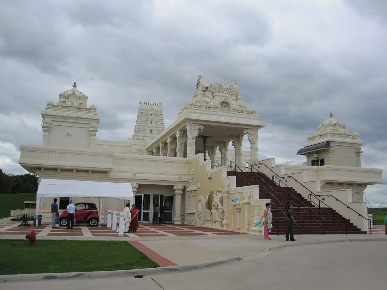 మబ్బులు కమ్మిన ఆకాశం కింద, క్రీమ్ రంగు గోపురం, ప్రవేశ మెట్లు, చెక్కిన ఏనుగు శిల్పంతో ఇల్లినాయ్‌లోని ఆరోరాలో ఉన్న శ్రీ వేంకటేశ్వర స్వామి (బాలాజీ) ఆలయ ముఖభాగం