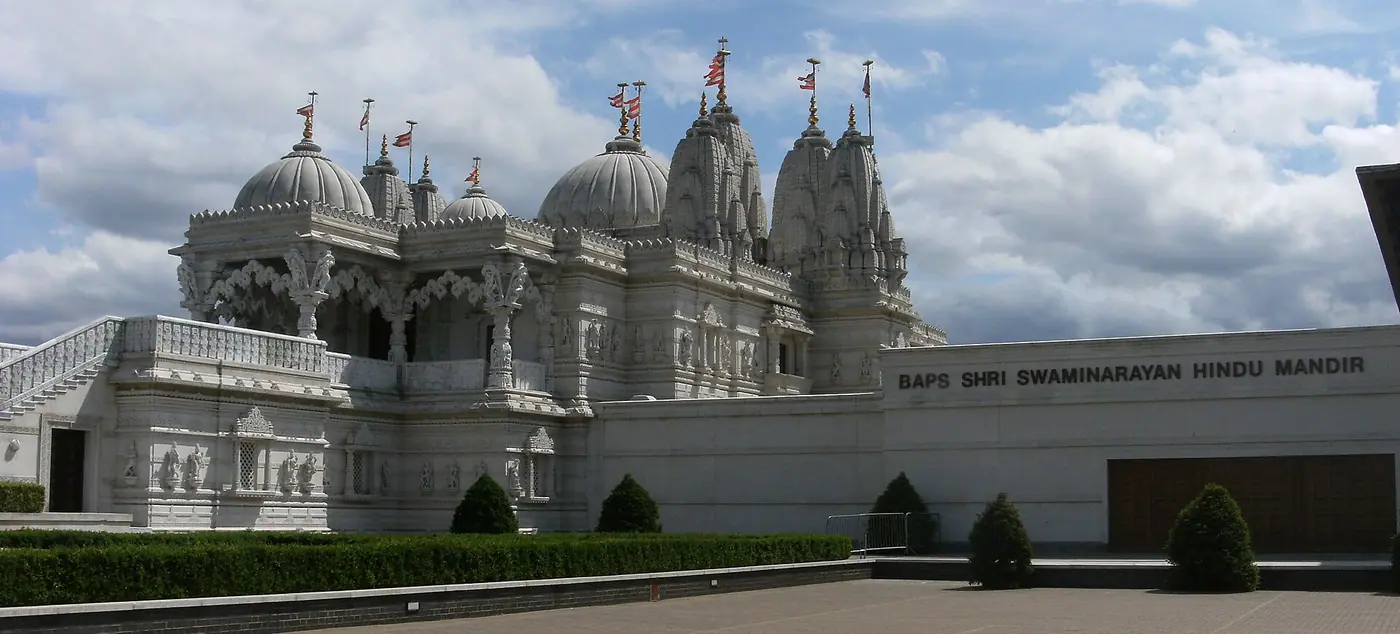 BAPS Shri Swaminarayan Mandir at Neasden, London, white stone domes and spires under a cloudy sky
